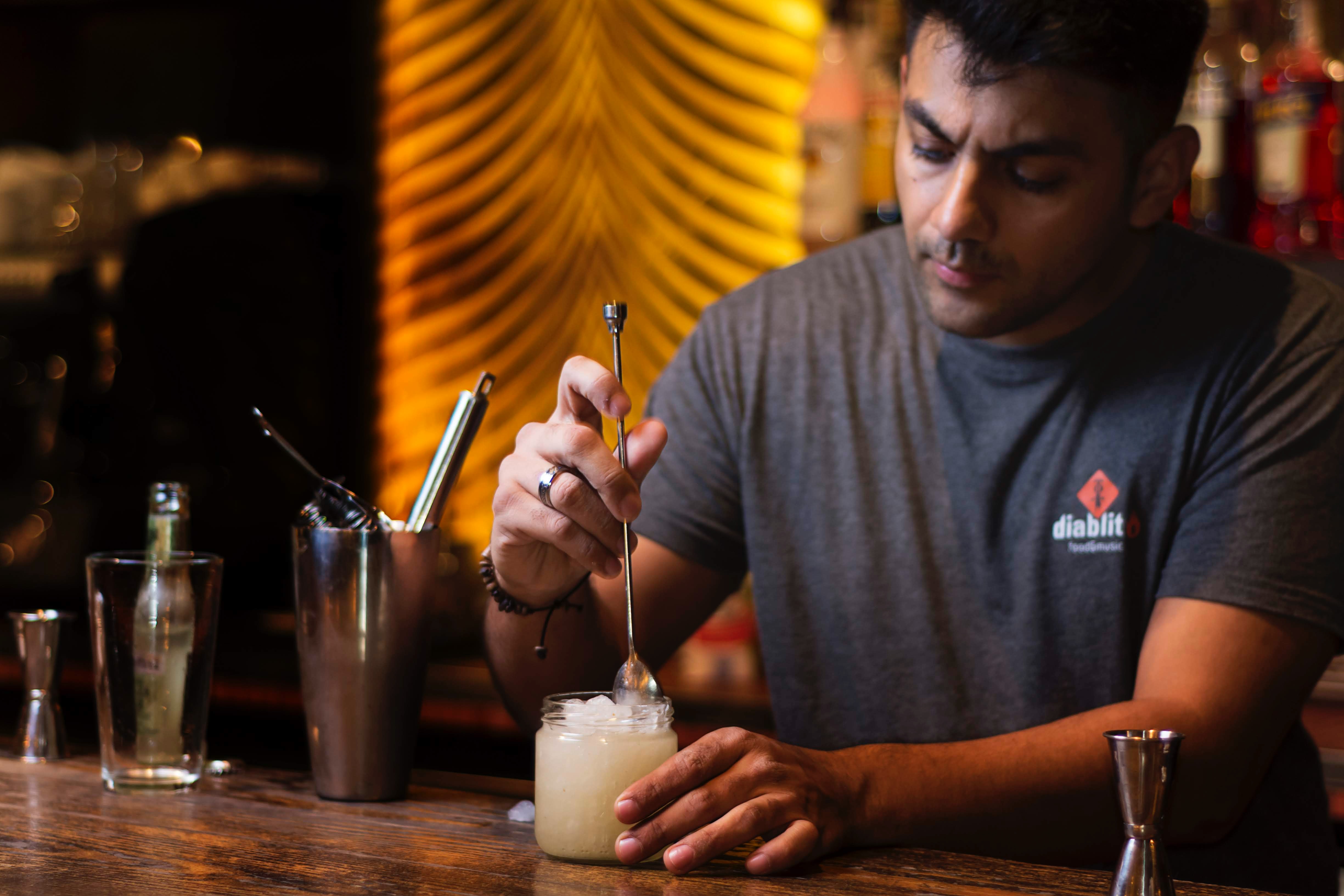 Bartender using a bar spoon to stir cocktail.