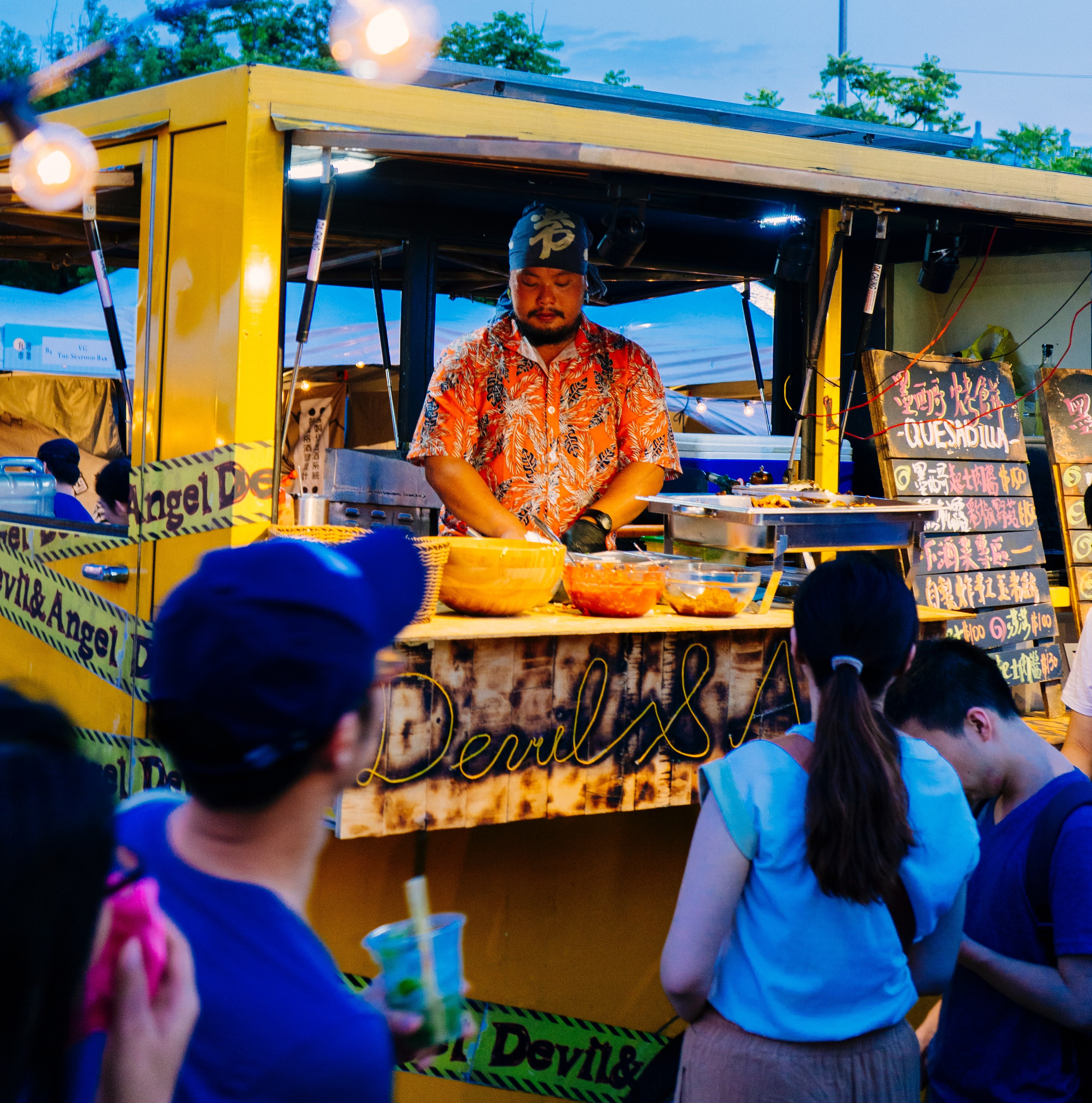 A man serving patrons from a yellow food truck