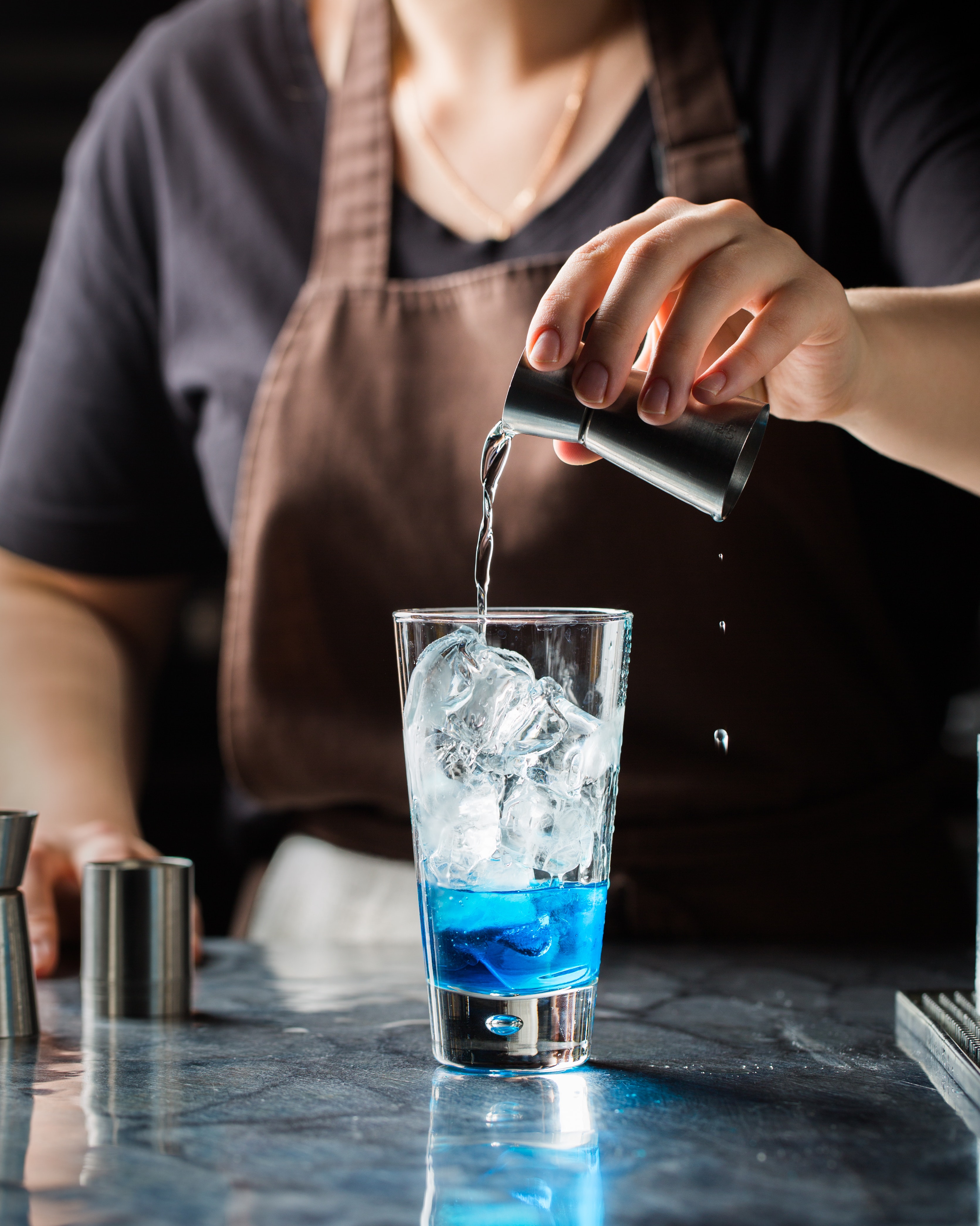 A jigger pouring alcohol into a glass.