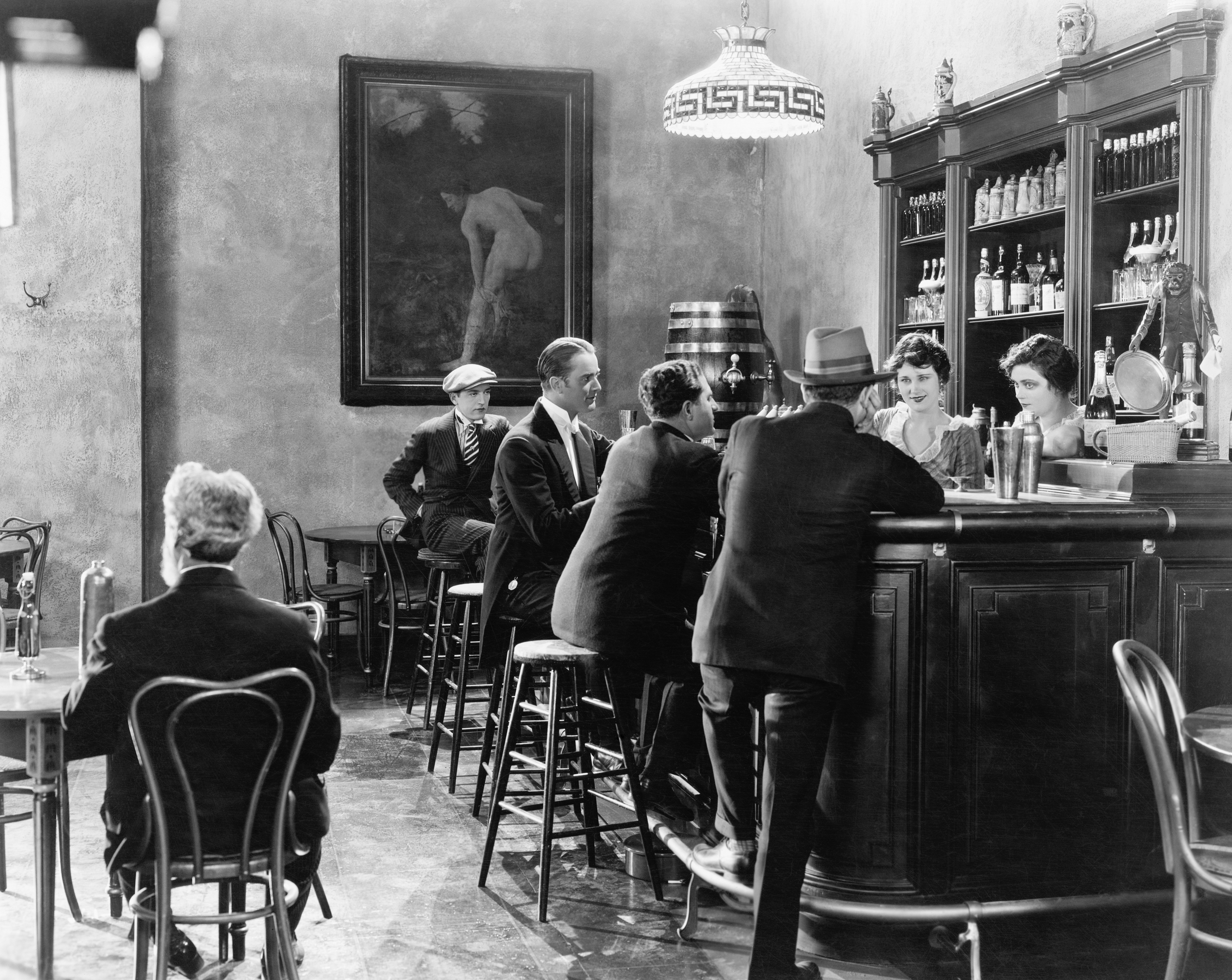 Men gathered around a bar with women bartenders