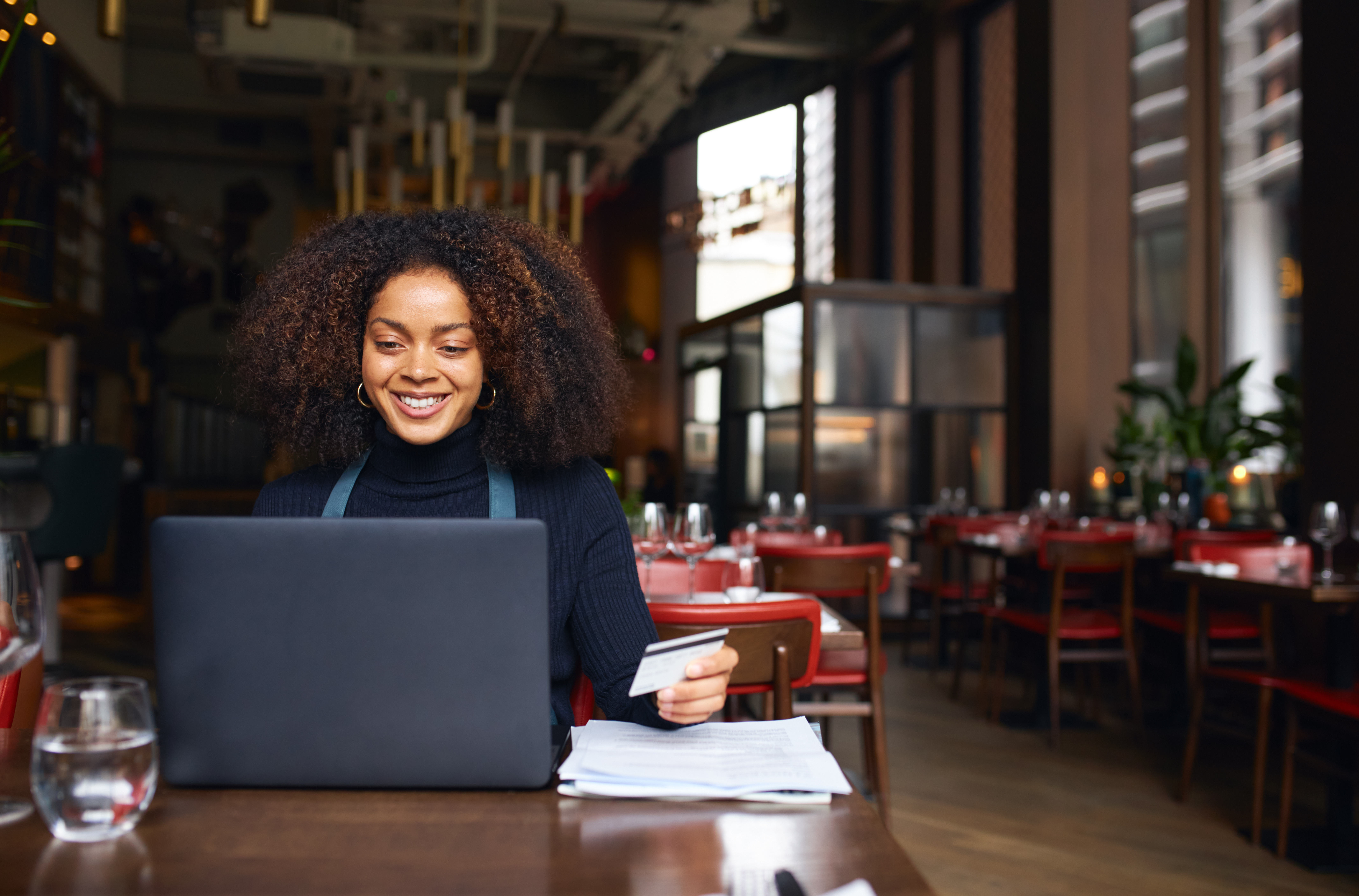 A woman works on a laptop at a bar or restaurant