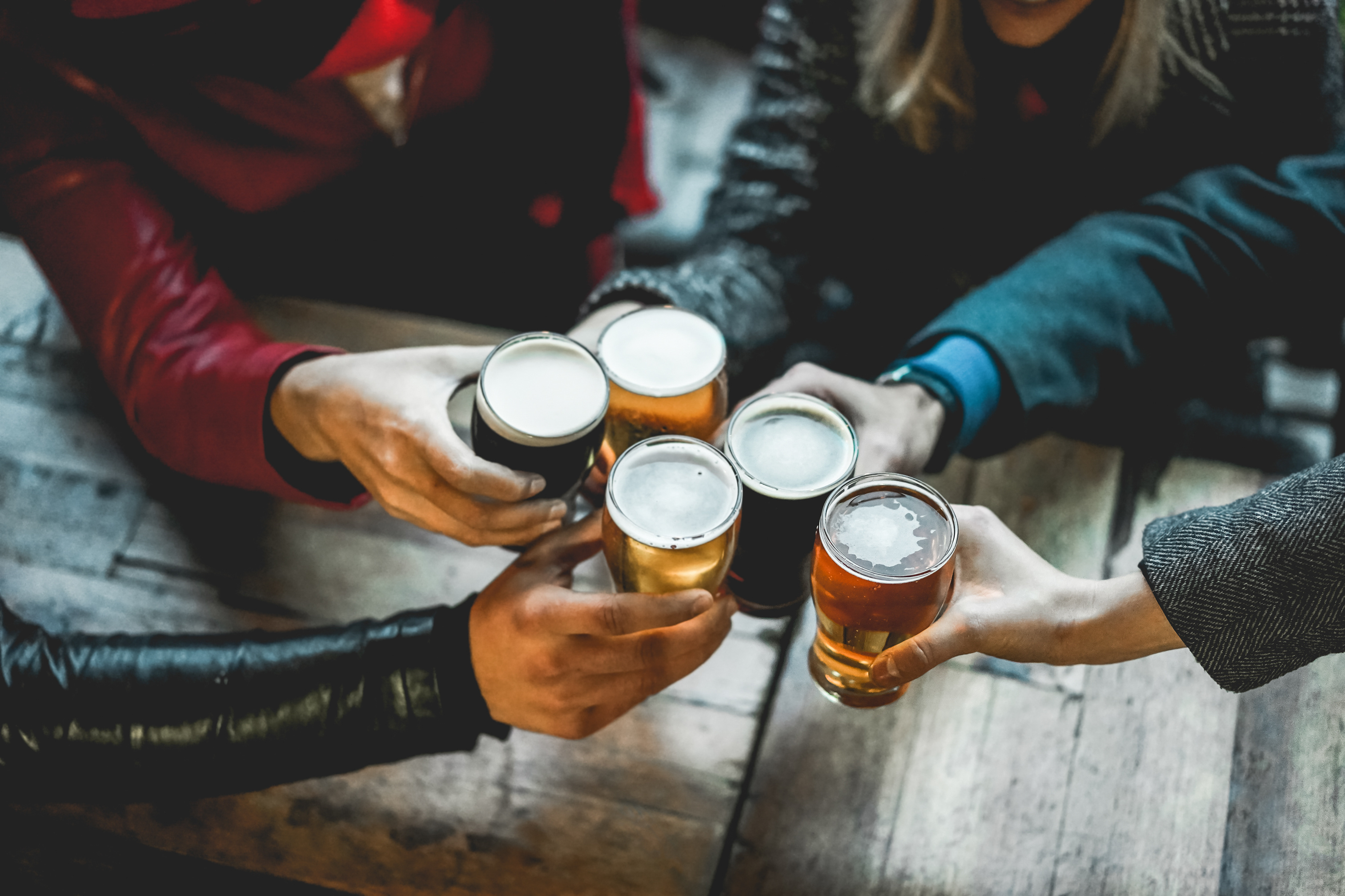 People gathered at a table toasting with beer glasses full of varying beer styles