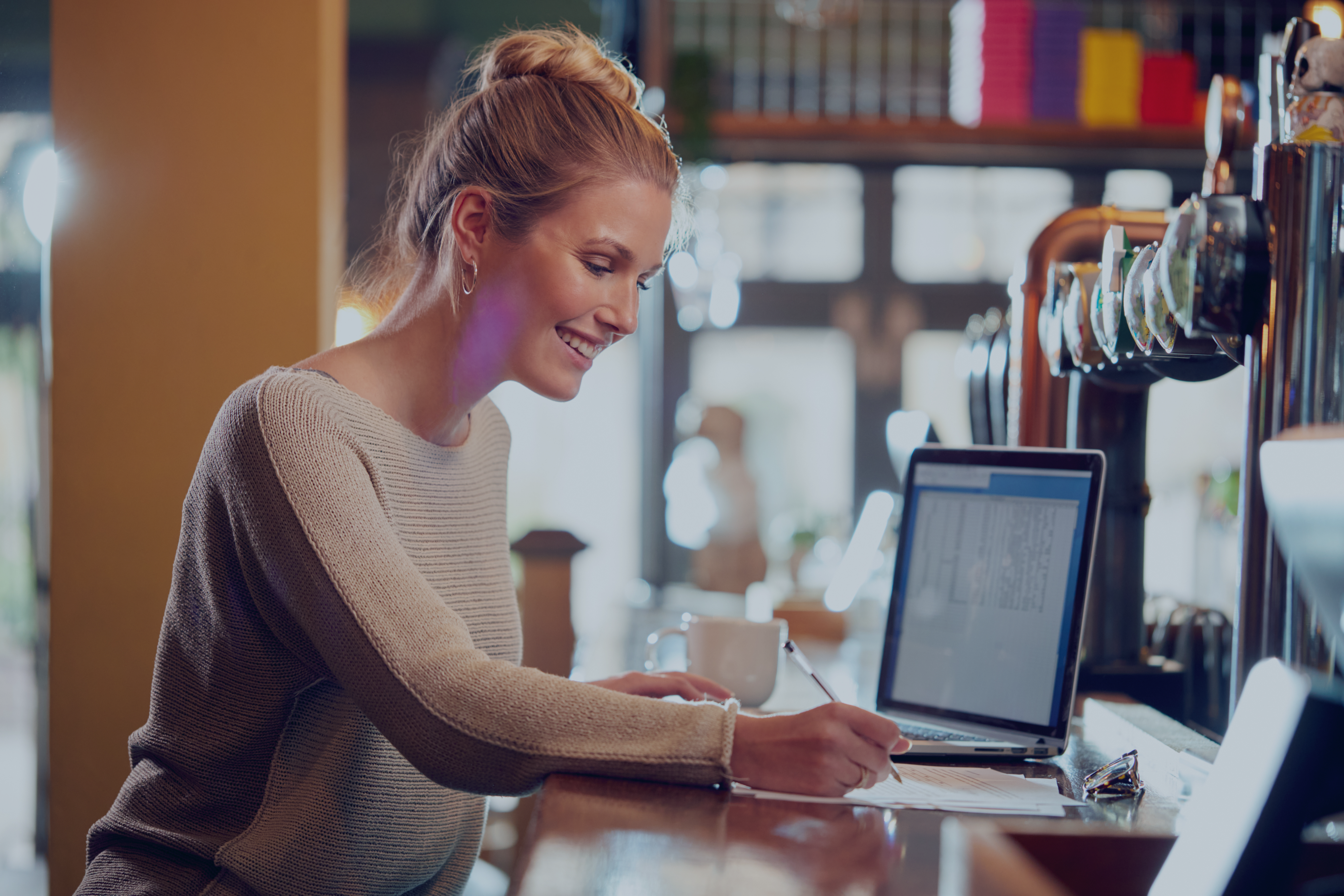 Woman working on laptop at a bar