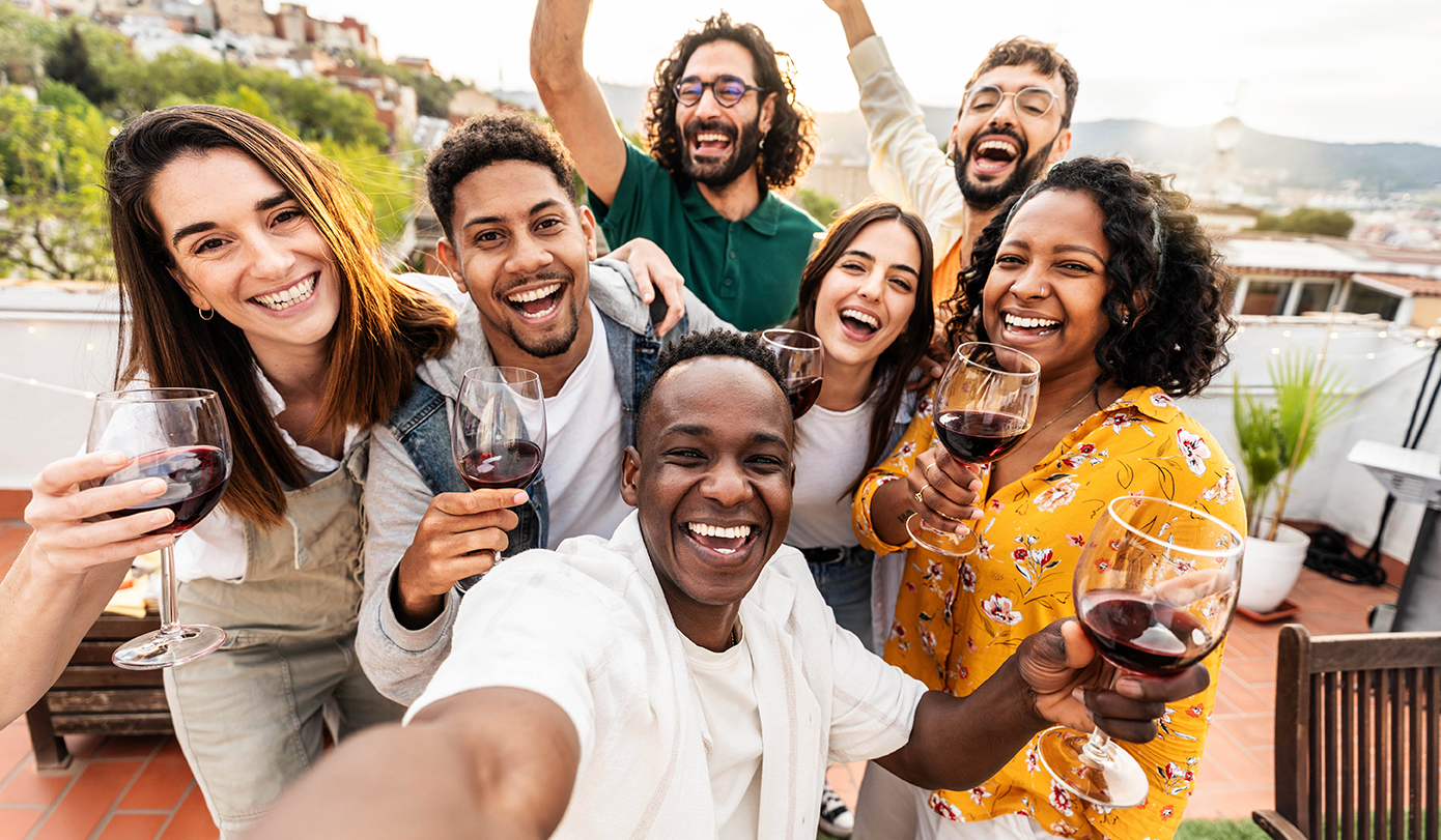 Young people celebrating on roof with red wine