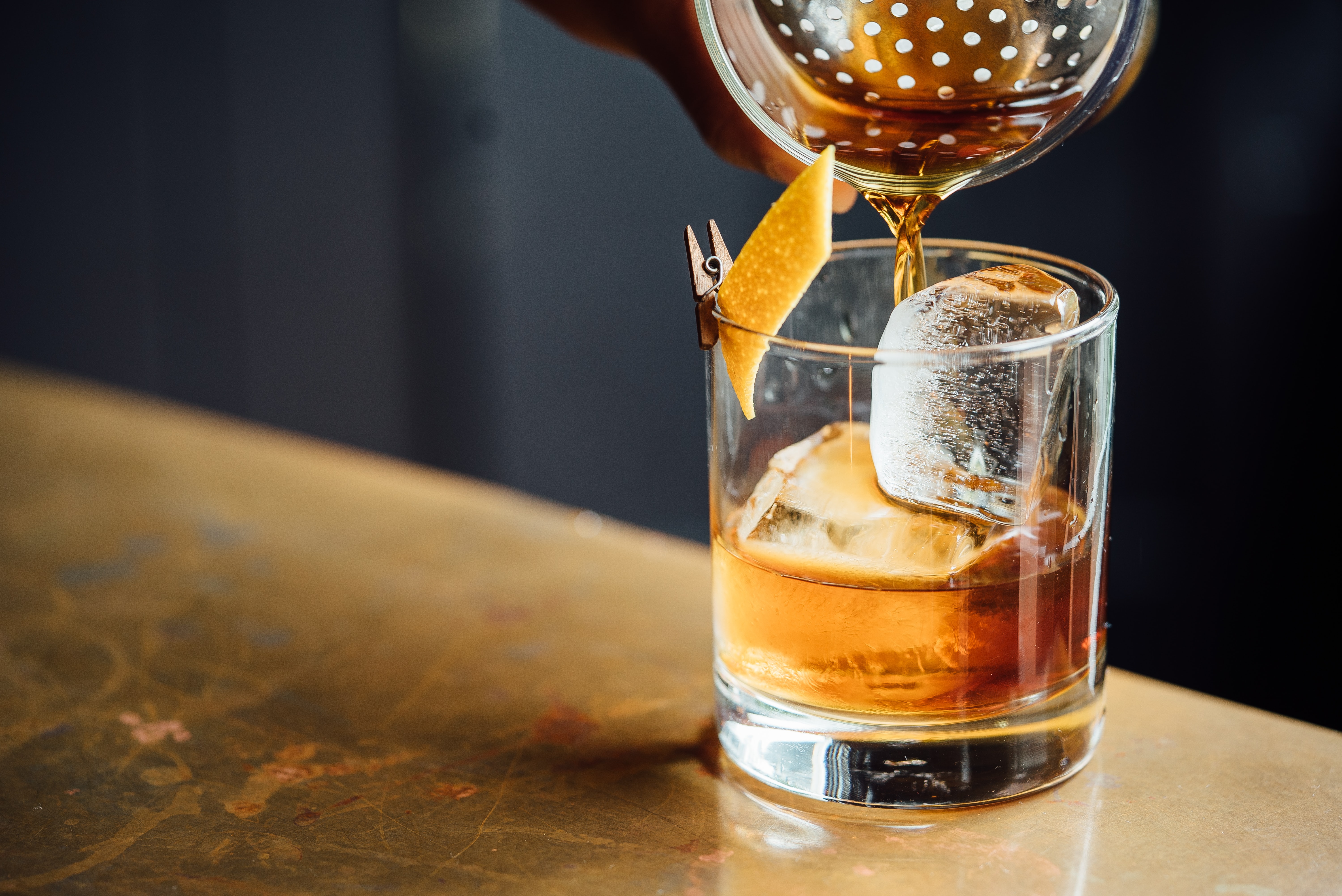 An old fashioned in a lowball glass with a large ice cube and an orange  peel