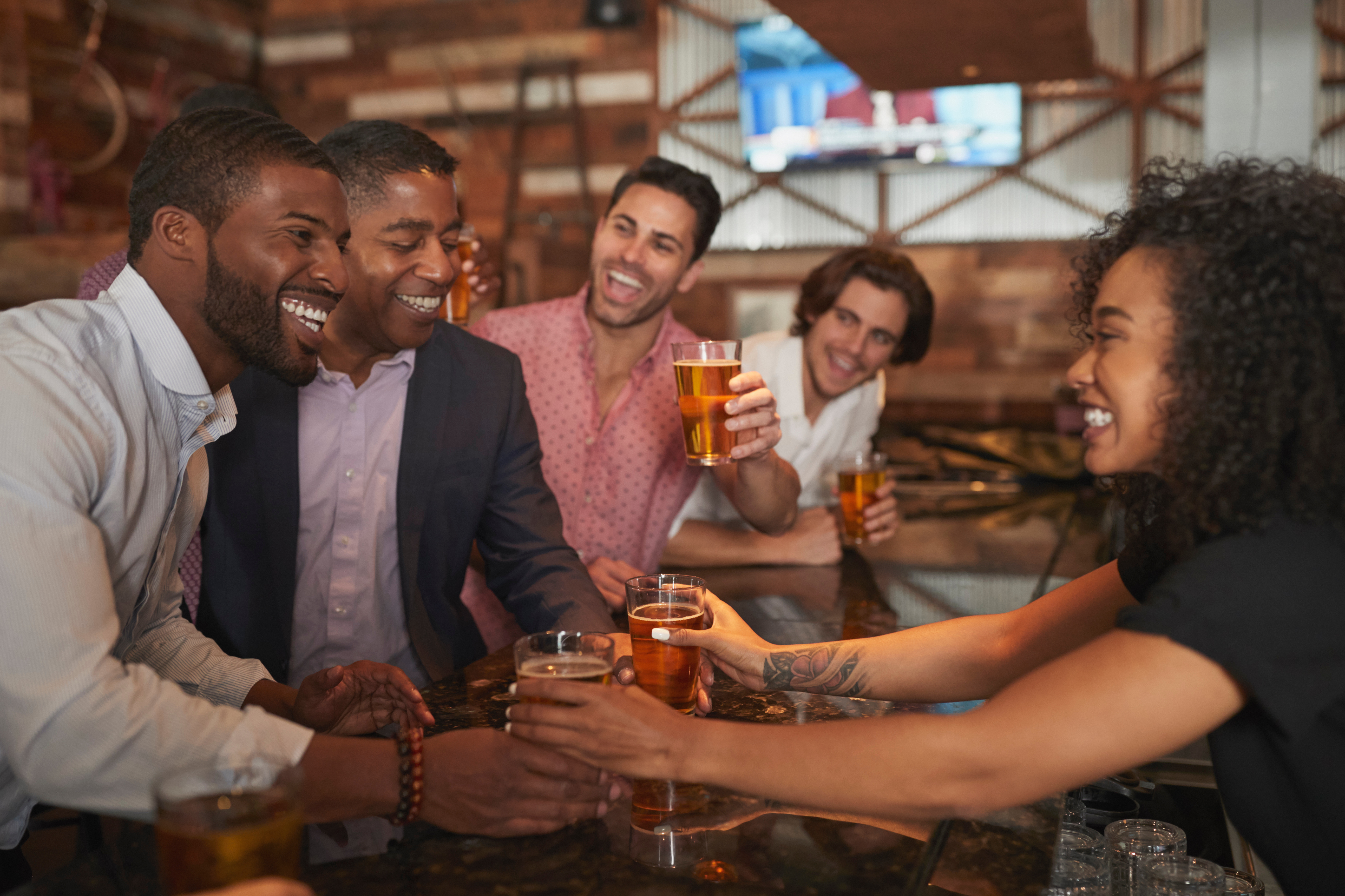 Black bartender serving diverse customers.