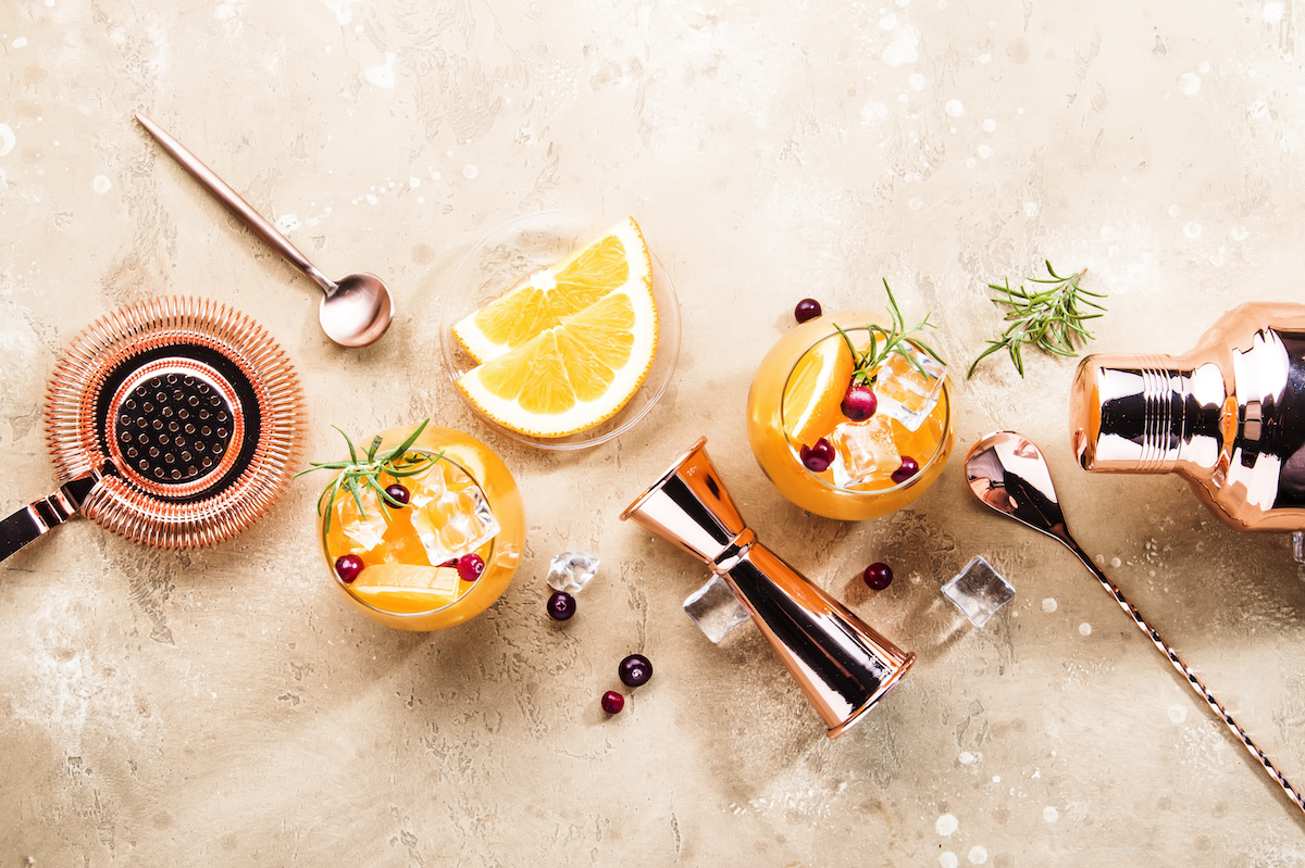 A collection of citrus fruits and berries with mixology equipment.