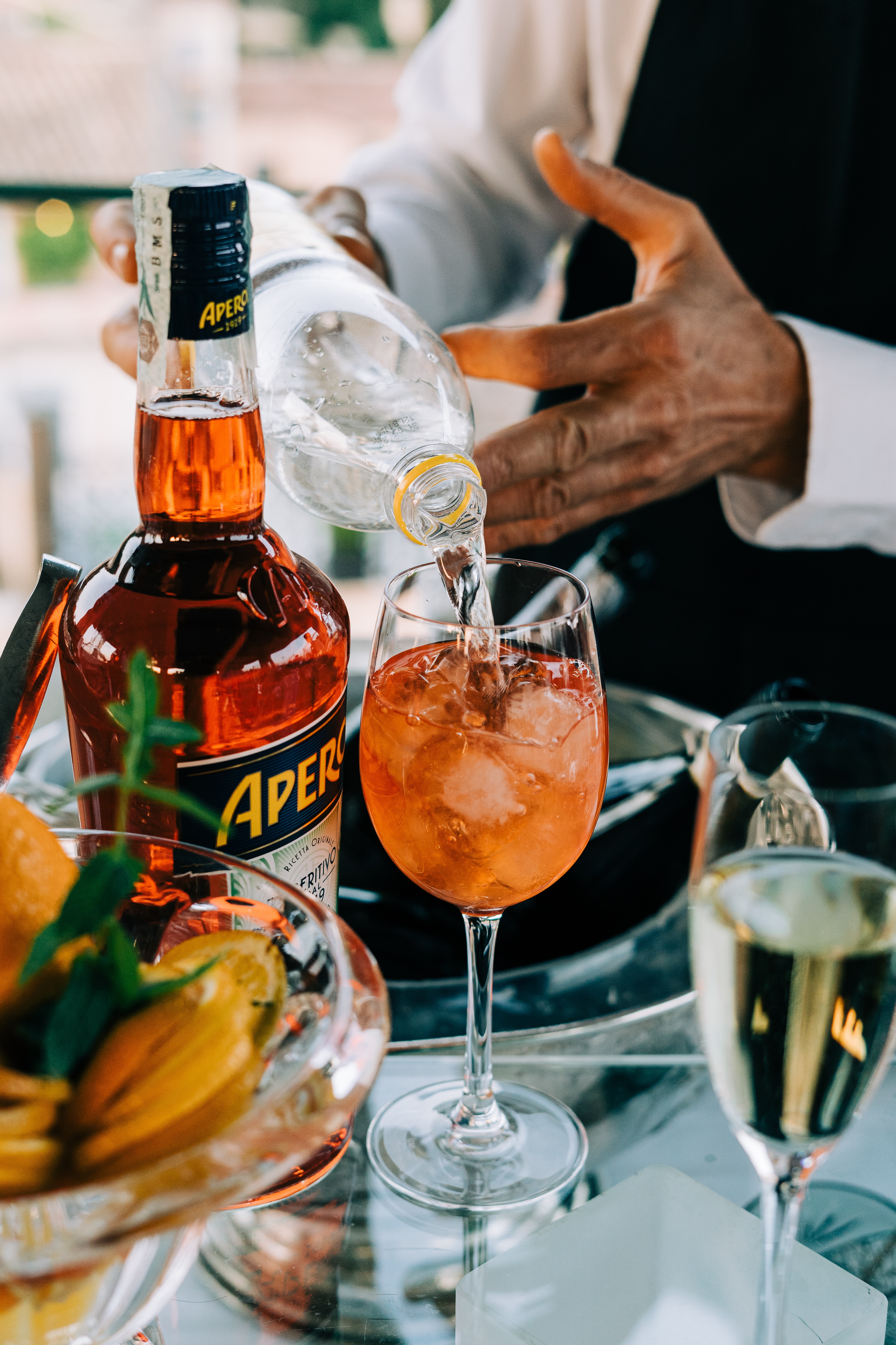 A bottle of aperol next to a aperol spritz